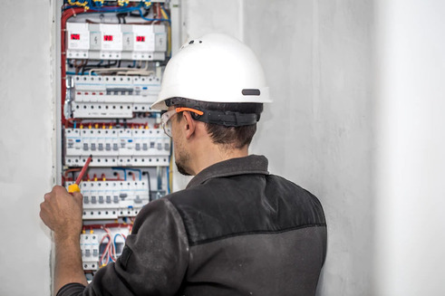 electrical technician working on a switchboard with fuses